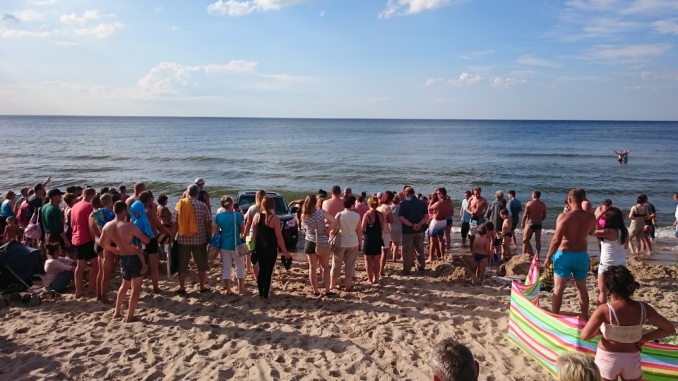 Kilkudziesięciu plażowiczów próbowało pomóc turyście, którego auto utknęło przy brzegu na plaży w Pobierowie. Fot. Wojciech Zwoliński