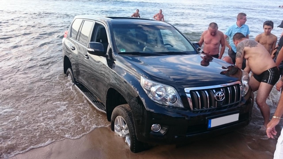 Kilkudziesięciu plażowiczów próbowało pomóc turyście, którego auto utknęło przy brzegu na plaży w Pobierowie. Fot. Wojciech Zwoliński