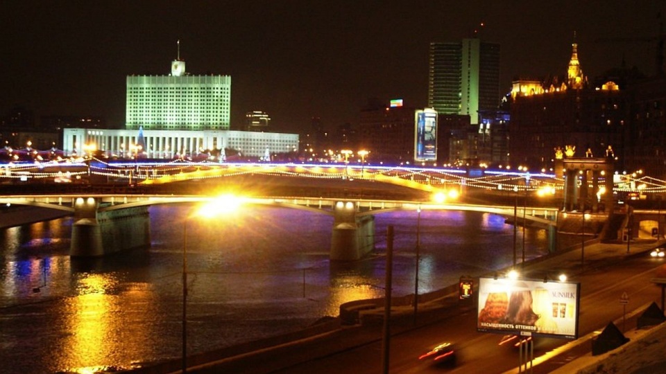 Moskwa nocą. Na pierwszym planie most metra nad rzeką Moskwą, na drugim z lewej tzw. Biały Dom (obecnie siedziba rządu, wcześniej Rady Najwyższej RFSRR). Fot. źródło: wikimedia.org/wikipedia/commons/6/6e/Moscow_at_night_2005.