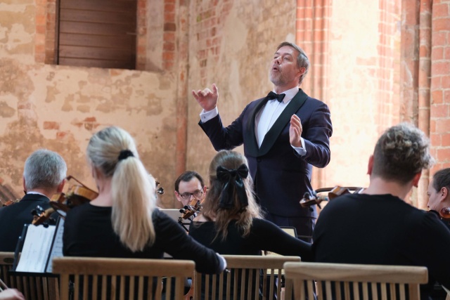 Przemysław Neumann dyryguje Orkiestrą Symfoniczną Filharmonii w Szczecinie na festiwalu Choriner Musicsommer w Niemczech. Fot. Dariusz Gorajski Szczecińscy filharmonicy w Chorin. To preludium do obchodów 150. rocznicy urodzin Karłowicza [ROZMOWA, ZDJĘCIA]