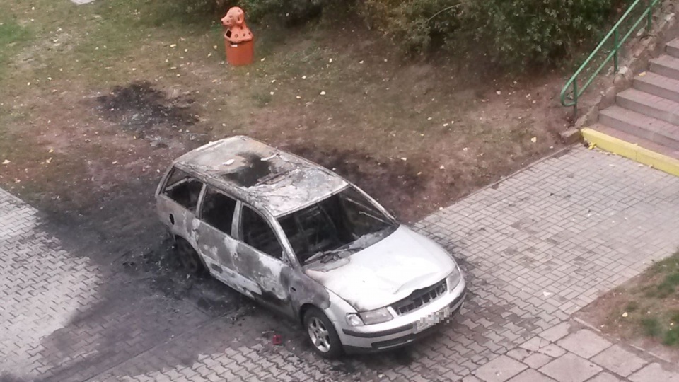 Spalony wrak auta stoi na placu między blokami. Fot. Słuchacz