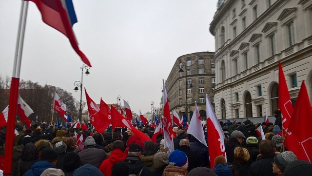 W demonstracji uczestniczą przedstawiciele partii opozycyjnych oraz Komitetu Obrony Demokracji. Manifestujący trzymają biało-czerwone i unijne flagi.