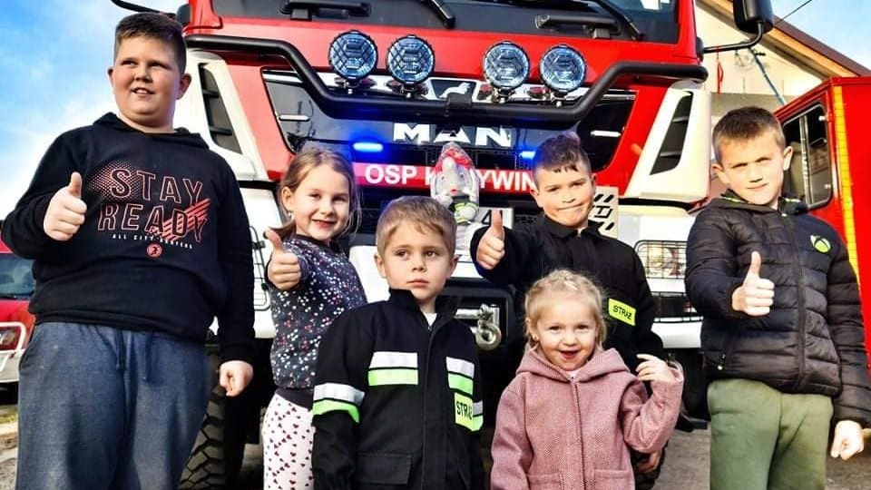 Z okazji chrztu nowego wozu najmłodsi mogli poznać pracę strażaków: wsiąść do samochodu, przygotować sprzęt do użycia wody oraz założyć strażackie kaski. źródło: OSP Krzywin