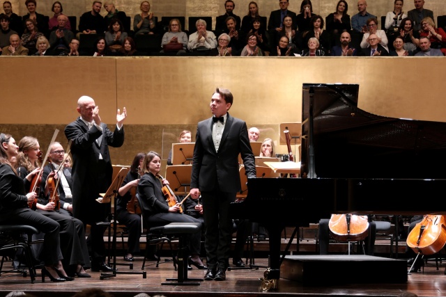 Mateusz Krzyżowski – pianista przyjmuje gorące brawa publiczności i dyrygenta Michała Klauzy. Fot. Cezary Aszkiełowicz Owacyjne przyjęcie Mateusza Krzyżowskiego i Michała Klauzy w Filharmonii [ZDJĘCIA]