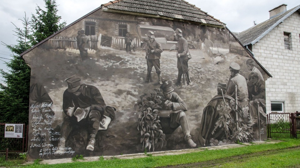 Mural przedstawiający żołnierzy kapitana Władysława Raginisa na ścianie jednego z domów w Wiźnie. To odwzorowanie autentycznego zdjęcia wykonanego 10 września 1939 r. Fot. Wikipedia / Arkadiusz Zarzecki (CC BY-SA 3.0)