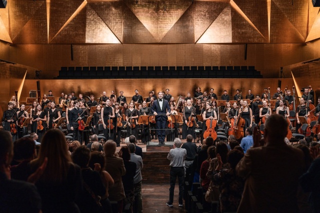 Maestra Przemysław Neumann przyjmuje owacyjne brawa publiczności z Internatiol Lutosławski Youth Orchestra. Fot. Piotr Nykowski Zofia Anna Olesik i orkiestra ILYO owacyjnie przyjęci w Złotej Sali Filharmonii [ZDJĘCIA]